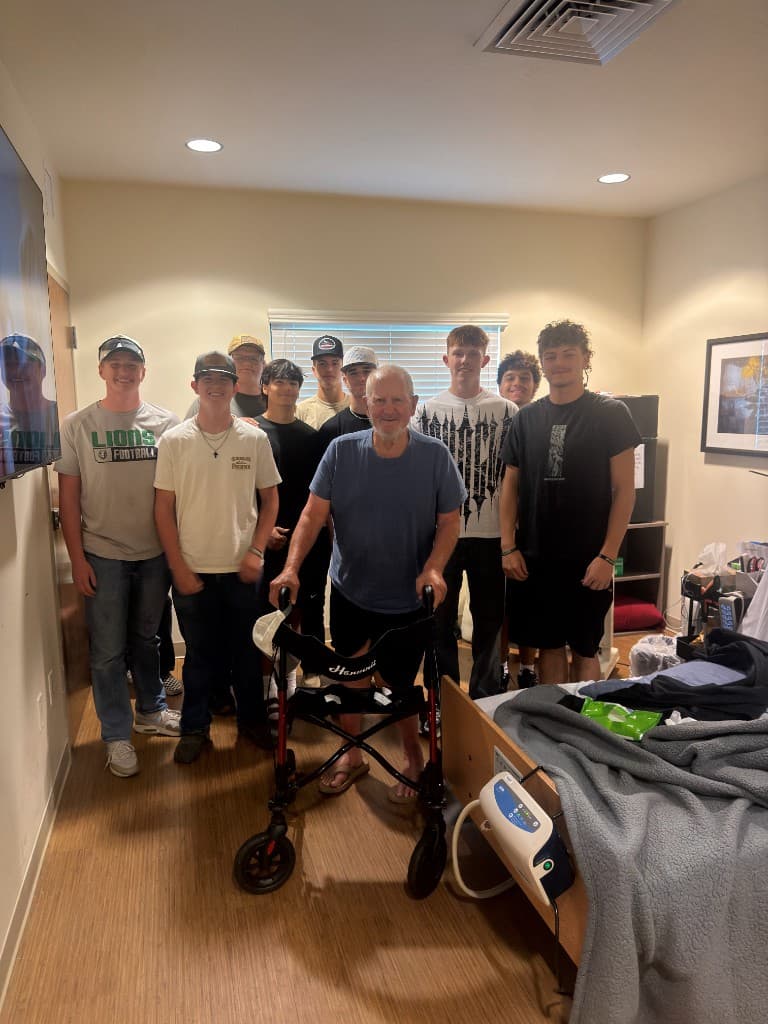 Payson Lions football players visiting a local veteran standing with a walker
