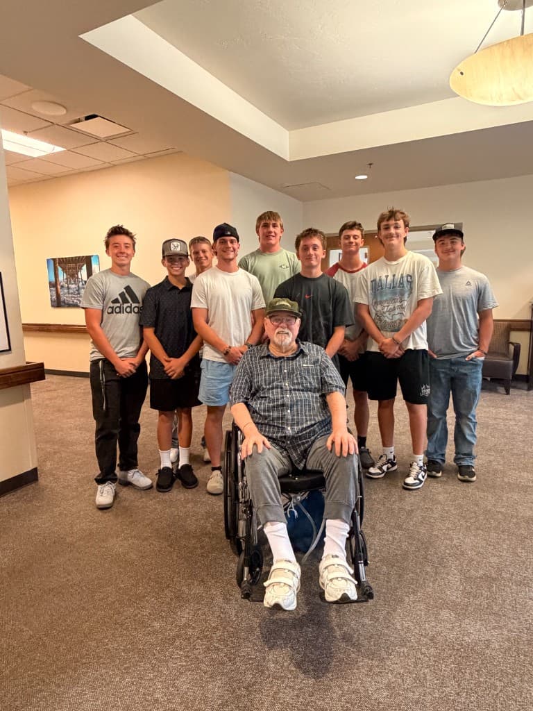 Payson Lions football players visiting a local veteran seated in a wheelchair
