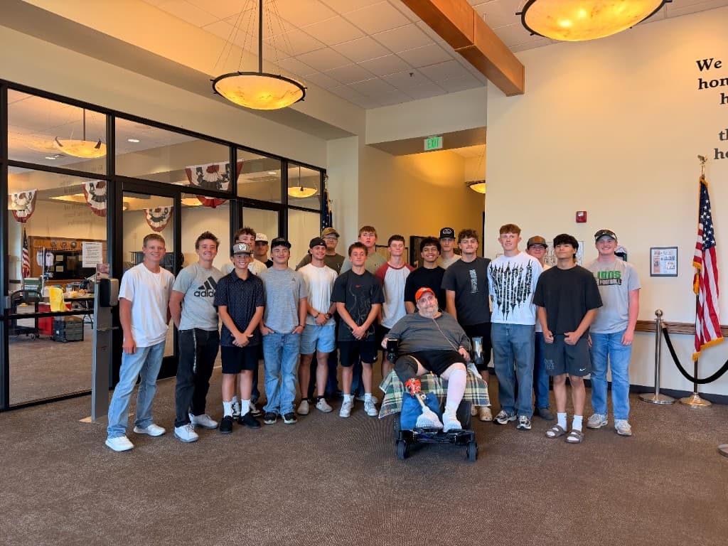 Payson Lions football players gathered with a local veteran during a Community Heroes Night visit